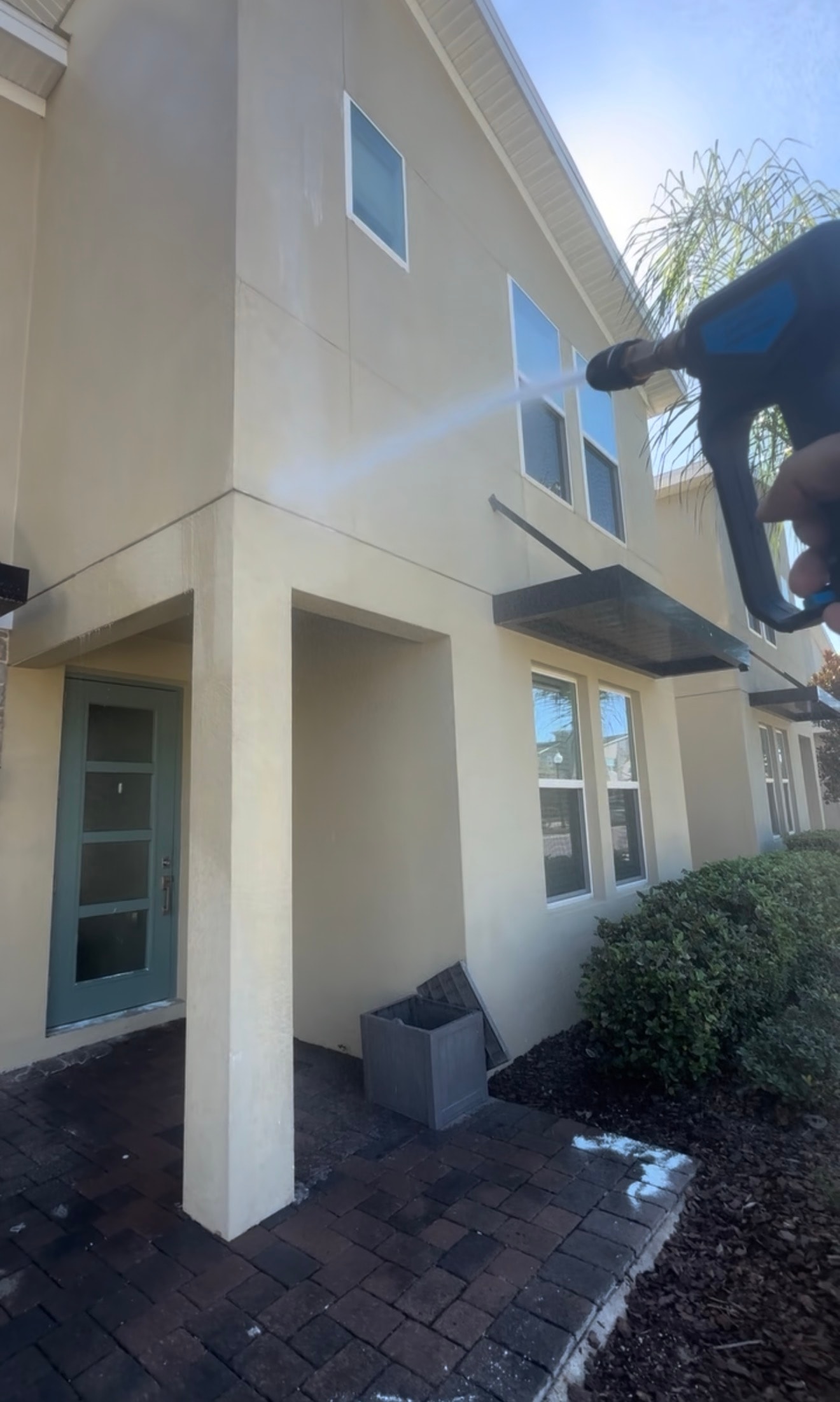 Bio-Cleaning Services performing pressure washing on a residential exterior.